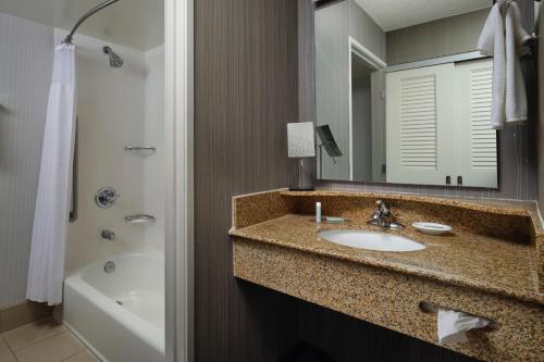 a bathroom with a sink and a mirror and a tub at Courtyard by Marriott Stockton in Stockton