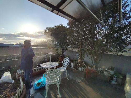 a man standing on a patio with a table and chairs at 幽舍の庭 in Izumi-Sano