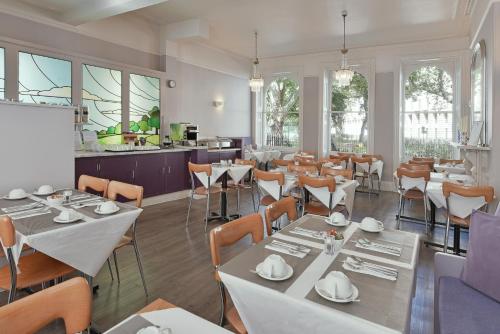 ein Restaurant mit weißen Tischen, Stühlen und Fenstern in der Unterkunft Harlingford Hotel in London