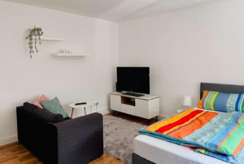 1 dormitorio con 1 cama, TV y silla en Gemütliches 1-Zimmer Appartement, en Langen
