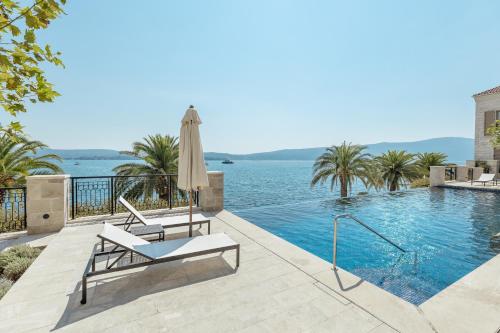 a swimming pool with a chair and an umbrella at Porto Montenegro in Tivat