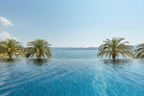 a swimming pool with palm trees and a body of water at Porto Montenegro in Tivat