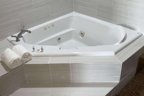 a white bath tub in a white tiled bathroom at Comfort Suites Near Seaworld in San Antonio