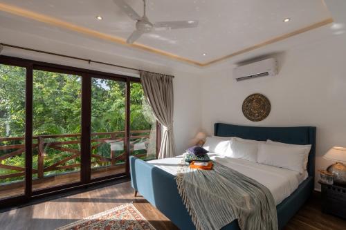 a bedroom with a bed and a balcony at Elivaas Indah Luxe 4BHK Villa with Pvt Pool, Moira in Old Goa