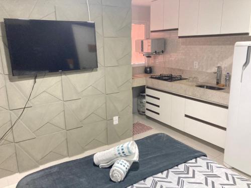 a kitchen with white cabinets and a tv on a wall at Jr FLATS in João Pessoa