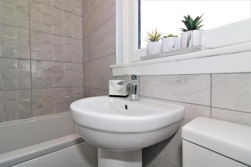 a white bathroom with a sink and a bath tub at Signature - Moore View in Hamilton