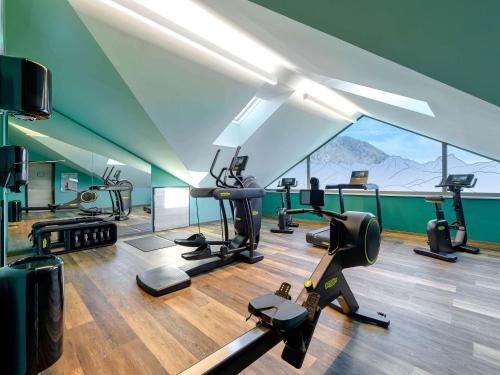 a gym with exercise equipment in a room with a mountain view at ibis Styles Bad Reichenhall in Bad Reichenhall