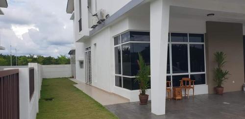 Casa blanca con patio con plantas en Homestay Fe-feeling Artis with 4 Bedrooms, en Rawang