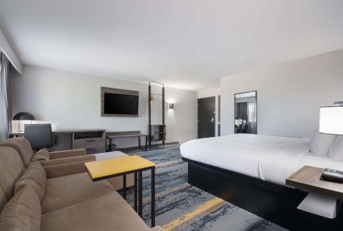 a hotel room with a large bed and a couch at Clarion Pointe OKC Airport in Oklahoma City