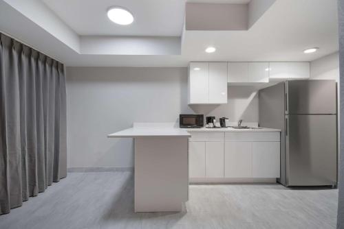 a kitchen with white cabinets and a refrigerator at Clarion Pointe OKC Airport in Oklahoma City