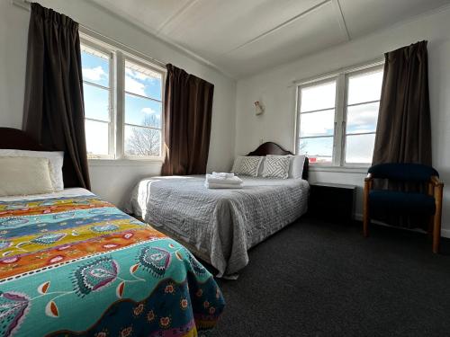 a hotel room with two beds and two windows at Rainbow Motel in Tauranga