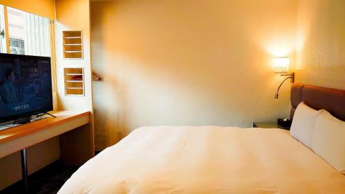 1 dormitorio con 1 cama blanca y TV en Hub Hotel Banqiao Branch en Taipéi
