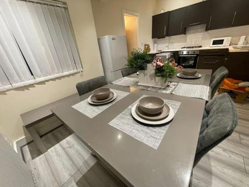 a kitchen with a dining table with chairs and a kitchen with a refrigerator at Big 1 Bedroom London House 2 bathroom in Plumstead