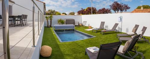 a backyard with a swimming pool and chairs and grass at Villa Ernie in Saint-Martin-de-Ré