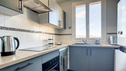 uma cozinha com armários brancos e um lavatório em 15 mn de PARIS, perle rare avec vue - 2 chambres em Groslay