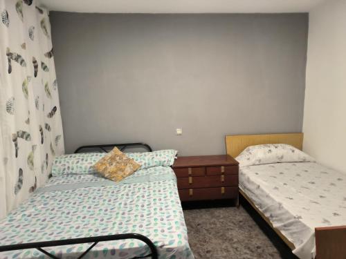 a bedroom with two beds and a dresser in it at La casa del Viajero in Puertollano