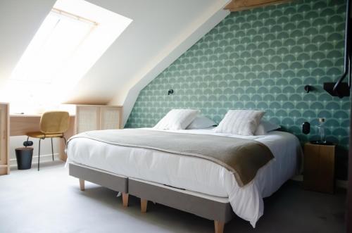a bedroom with a large bed with a green wall at DOMAINE LE MEZO in Ploeren