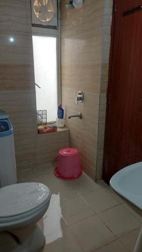 bagno con servizi igienici e ciotola rosa sul pavimento di Home Stay 2 a Noida