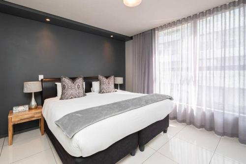 1 dormitorio con cama grande y ventana grande en One Bedroom Seaside Elegance, en Ciudad del Cabo