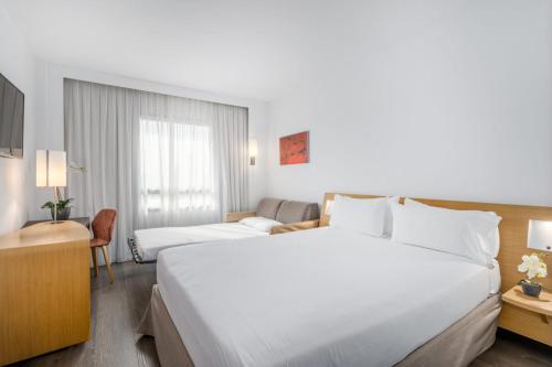 a hotel room with a large white bed and a couch at Exe Madrid Norte in Madrid
