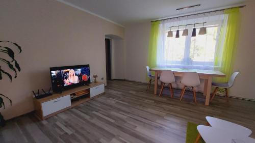 uma sala de estar com uma mesa de jantar e uma televisão em Moderní klidný apartmán v přírodě, s parkováním. em Nové Město nad Metují
