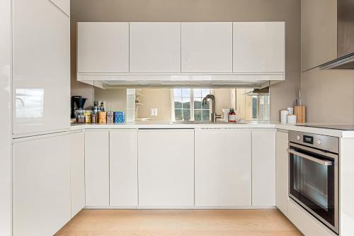 a white kitchen with white cabinets and a sink at Dinbnb Homes I Luxury Villa with Hot Tub & Views in Bergen