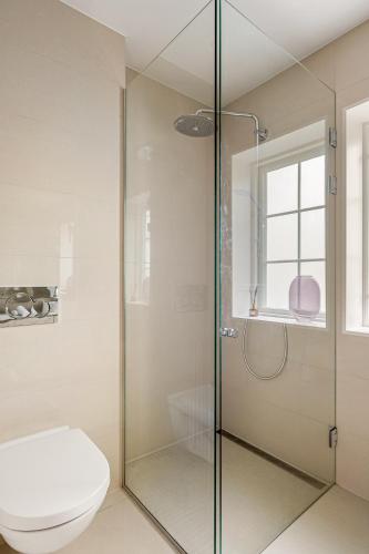 a bathroom with a glass shower with a toilet at Dinbnb Homes I Luxury Villa with Hot Tub & Views in Bergen