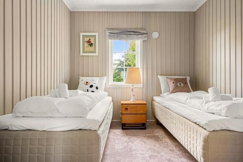two twin beds in a room with a window at Dinbnb Homes I Luxury Villa with Hot Tub & Views in Bergen