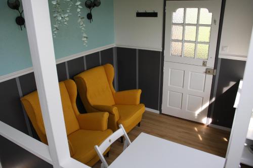 a room with two chairs and a door at Boerenchalet Dirk, Minicamping de Grutte Earen in Burum