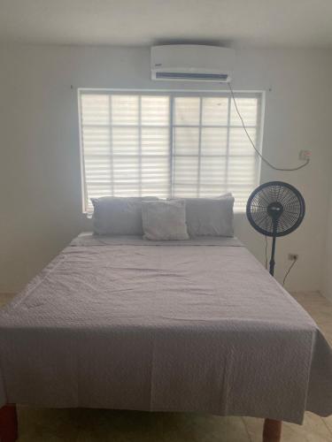 a bed in a bedroom with a window and a fan at 3-Bed House in Montego Bay 10 min from airport in Montego Bay