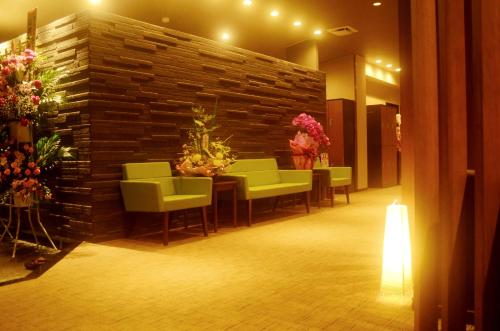 um átrio com uma parede de tijolos, mesas e cadeiras em Hotel Futabatei em Hirono