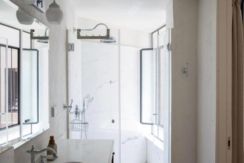 a white bathroom with a shower and a sink at David Zehavi Apt #2 in Tel Aviv