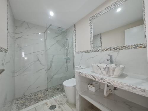 Un baño blanco con lavabo y ducha. en Apartamento 1134, en Zahara de los Atunes