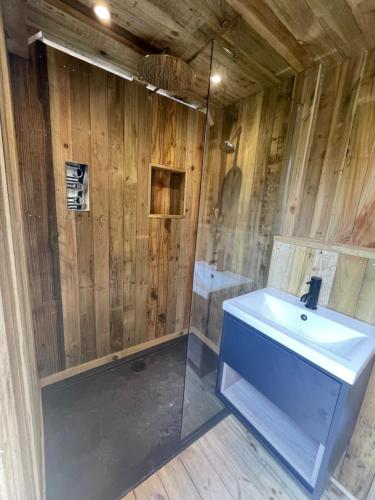 La salle de bains est pourvue d'un lavabo blanc et d'un mur en bois. dans l'établissement The Bell Tent - overlooking the moat with decking, à Evesham