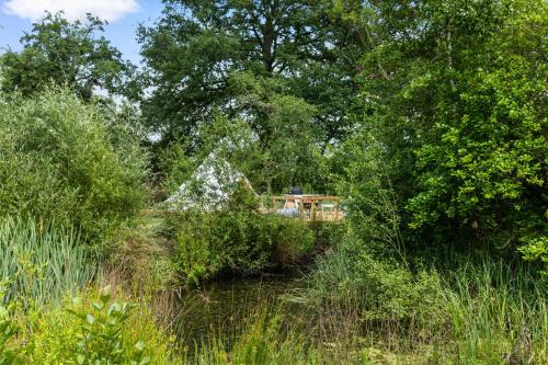 a garden with trees and a house in the distance at The Bell Tent - overlooking the moat with decking in Evesham