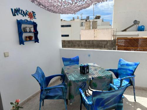 une table avec des chaises bleues dans une pièce avec un bâtiment dans l'établissement La Buganvilla rooms, à Arrecife