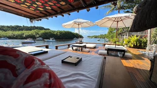 a deck with tables and umbrellas and a body of water at Casa Downtown in Caraíva