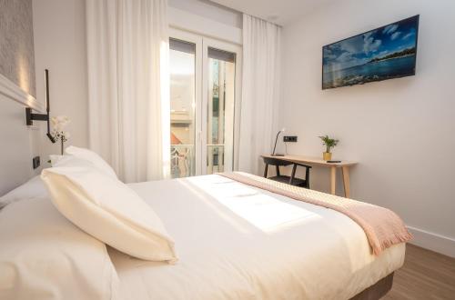 uma cama branca num quarto com uma janela em PRINCIPE DE VERGARA ROOMS Lujo en el centro de Logroño em Logroño
