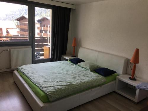 1 dormitorio con cama y ventana grande en Appartement plus Pool, Morgins, Portes du Soleil en Morgins