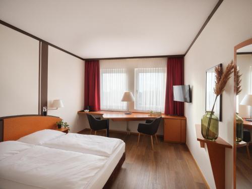 a hotel room with a bed and a desk at Mühlenhotel Halle-Leipzig in Landsberg