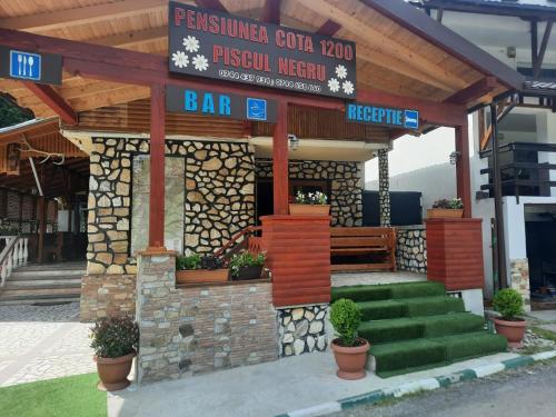 un bar con macetas delante de un edificio en Pensiunea Cota 1200 Piscul Negru en Arefu