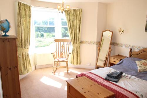 a bedroom with a bed and a chair and a window at Lake District 4 Bedroom House, Ings, Cumbria. in Kendal