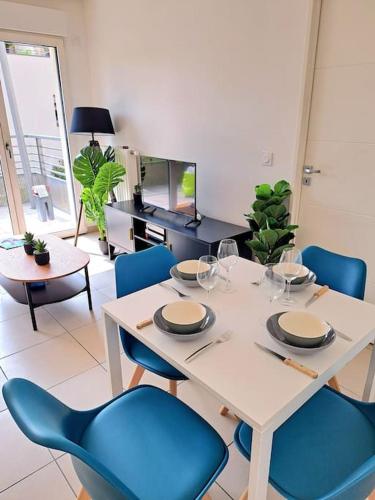 a dining room with a table and blue chairs at Casa Rosa : appartement moderne avec balcon in Tassin-la-Demi-Lune