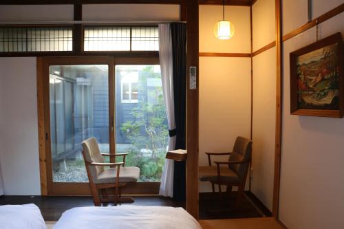 1 dormitorio con 1 cama, 2 sillas y ventana en Hostel Fish in a River en Takayama