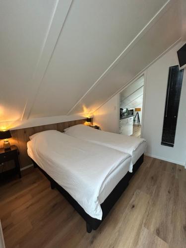 1 dormitorio con 1 cama blanca grande y suelo de madera en Boetje 51, en Den Burg