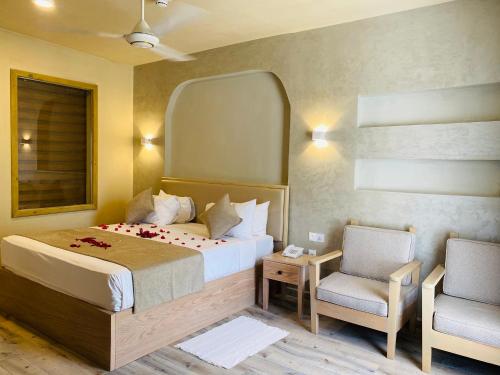 a bedroom with a bed with a mirror and a chair at Kiwengwa Beach Resort in Kiwengwa
