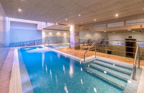 a large swimming pool with stairs in a building at Leonardo Hotel Fuengirola Costa del Sol in Fuengirola