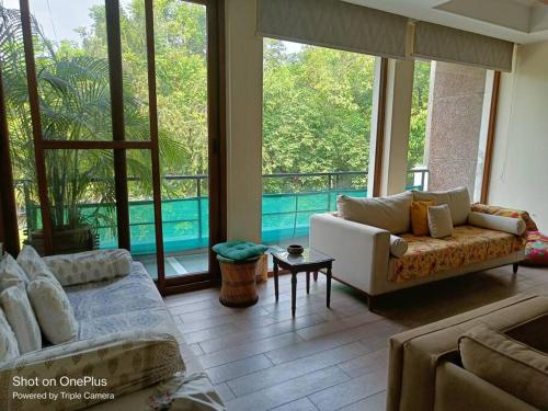 a living room with a couch and large windows at BnBBuddy-Majestic Home near NFC in New Delhi