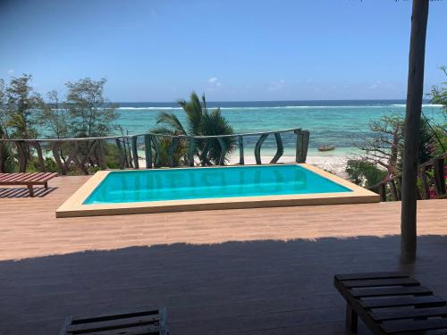 a swimming pool with the ocean in the background at Zi Villa Beach Cottage in Matemwe