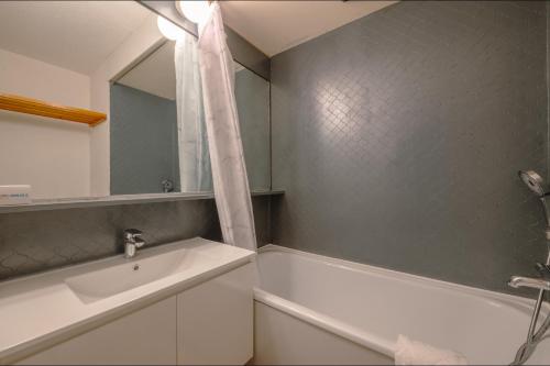 uma casa de banho com uma banheira, um lavatório e um espelho. em Chamonix Sud - Bâtiment Iris 374 - Happy Rentals em Chamonix-Mont-Blanc